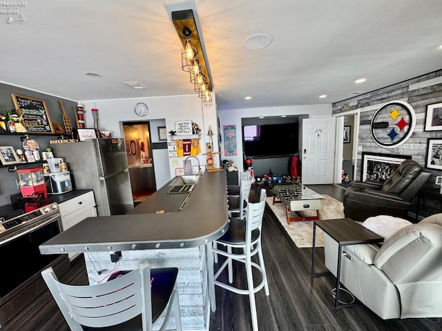 kitchen featuring stainless steel appliances, dark countertops, dark wood-type flooring, open floor plan, and a sink