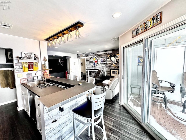 kitchen with visible vents, dark wood finished floors, a kitchen breakfast bar, a peninsula, and a fireplace