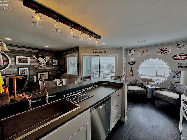 kitchen featuring open floor plan, stainless steel dishwasher, a sink, and white cabinets