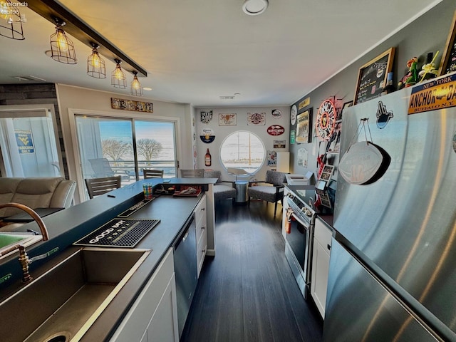 kitchen with dark countertops, white cabinetry, appliances with stainless steel finishes, and dark wood finished floors