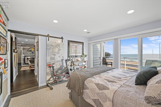 bedroom with a barn door, visible vents, wood finished floors, and recessed lighting