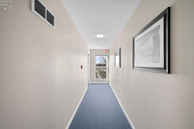 hall with baseboards, visible vents, and carpet flooring