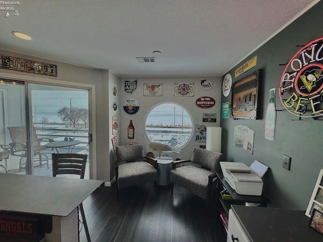 sitting room with visible vents, a textured ceiling, wood finished floors, and a wealth of natural light