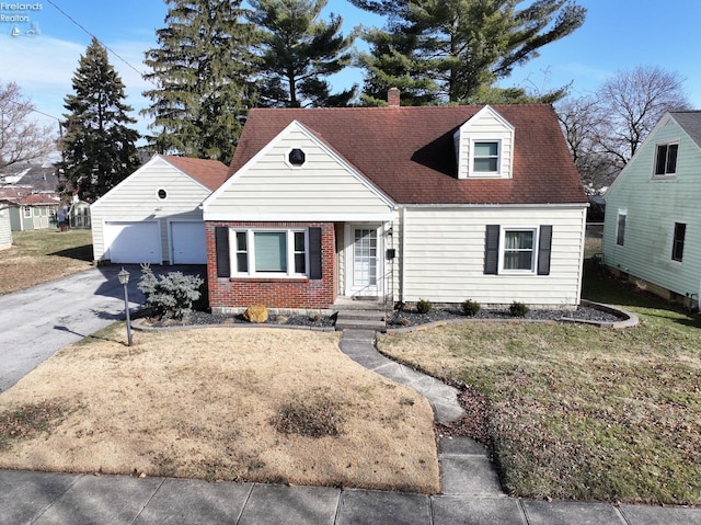 new england style home with an outbuilding, brick siding, a chimney, driveway, and a front lawn