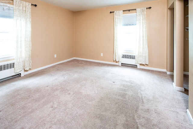 spare room with carpet, radiator heating unit, and baseboards