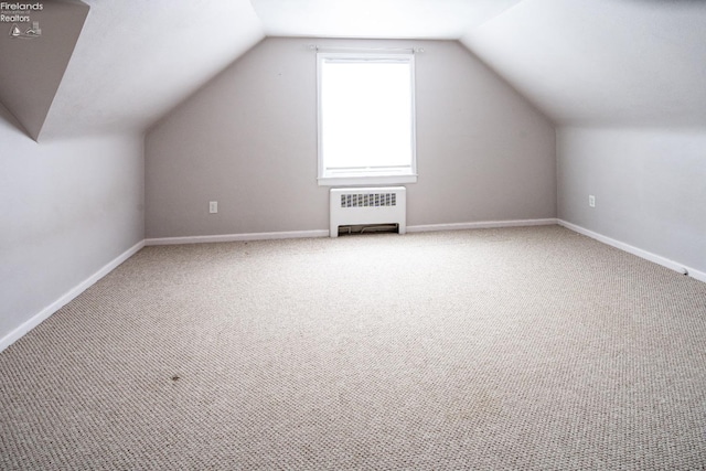 bonus room with lofted ceiling, radiator heating unit, carpet flooring, and baseboards