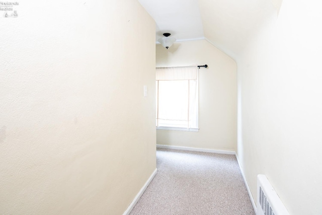 hallway featuring lofted ceiling, carpet, visible vents, and baseboards