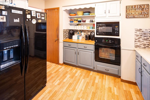 kitchen featuring light wood finished floors, tasteful backsplash, gray cabinets, light countertops, and black appliances