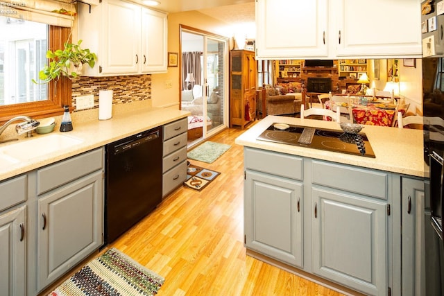 kitchen featuring black appliances, gray cabinets, light wood-type flooring, and a sink