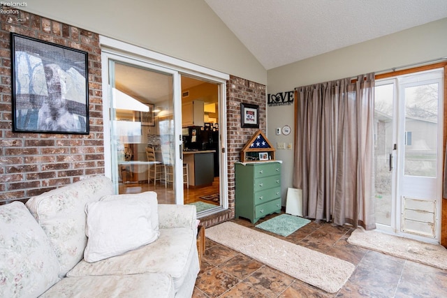 living room with stone finish flooring, vaulted ceiling, a textured ceiling, and brick wall