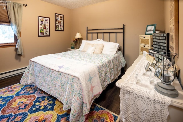 bedroom featuring a baseboard heating unit, a textured ceiling, and wood finished floors