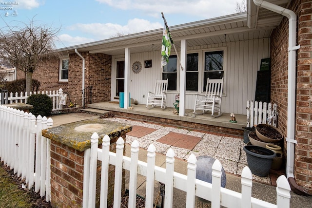 exterior space featuring a porch, fence, and brick siding