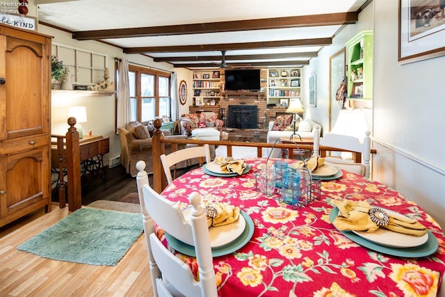 dining area featuring built in shelves, a fireplace, wood finished floors, and beam ceiling