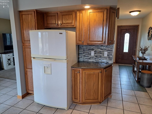 kitchen with brown cabinetry, freestanding refrigerator, decorative backsplash, and light tile patterned floors