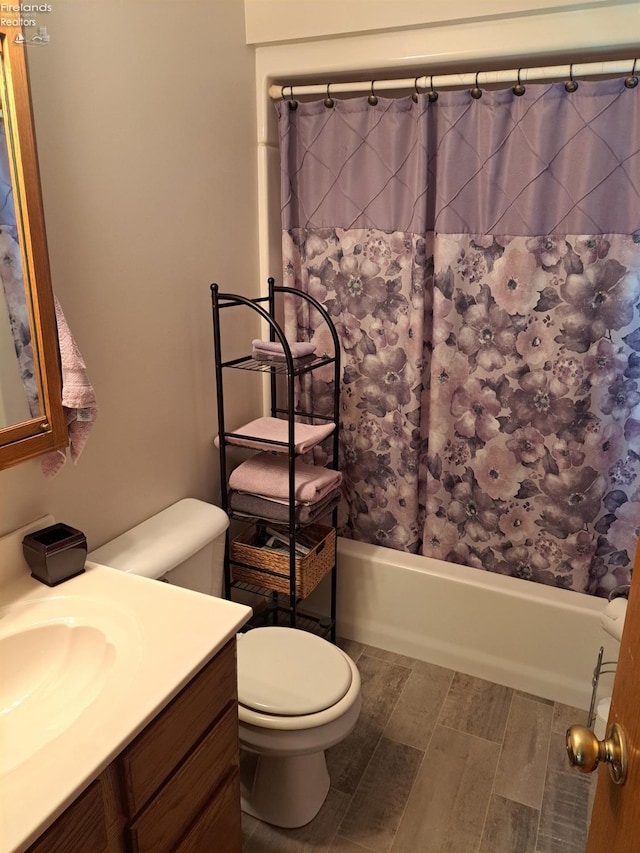 full bathroom featuring toilet, wood finish floors, shower / tub combo with curtain, and vanity