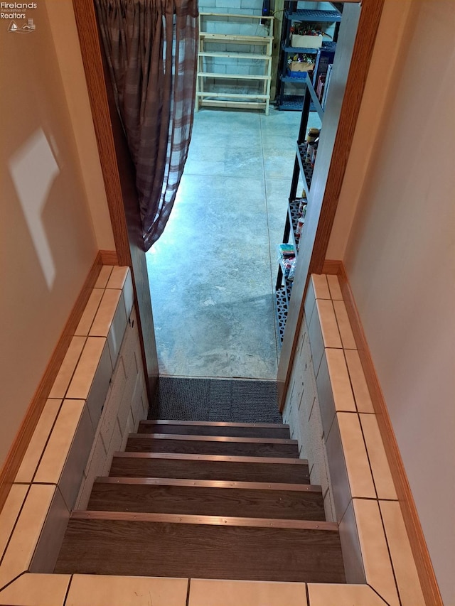 stairway with baseboards and tile patterned floors