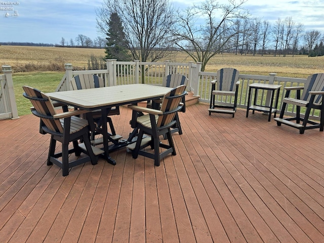 deck featuring a yard, a rural view, and outdoor dining space