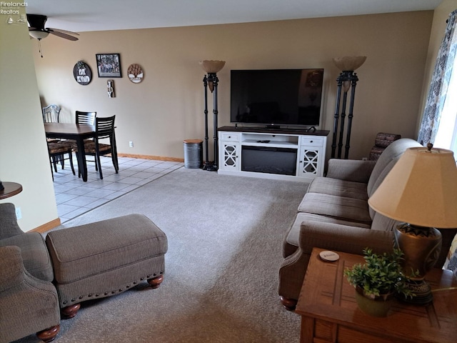 living room featuring carpet, ceiling fan, baseboards, and tile patterned floors