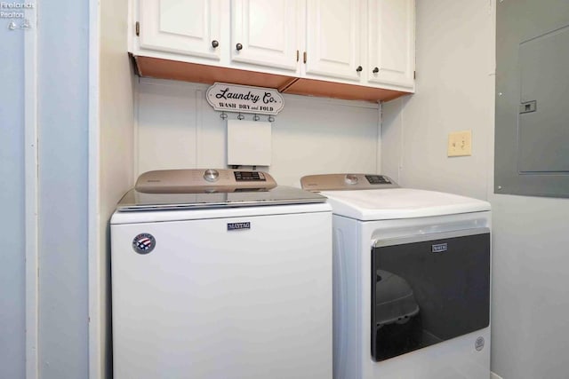 washroom featuring electric panel, washer and dryer, and cabinet space