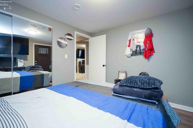 bedroom with a closet, baseboards, and wood finished floors