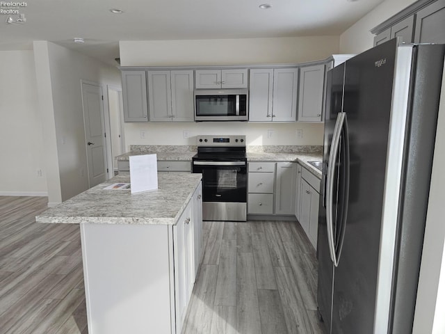 kitchen featuring stainless steel appliances, recessed lighting, gray cabinetry, light wood-style floors, and a kitchen island