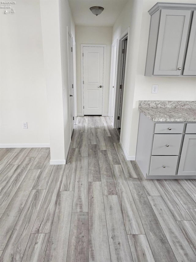 hallway featuring light wood-type flooring and baseboards