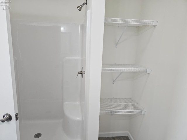 bathroom with a shower stall and a walk in closet