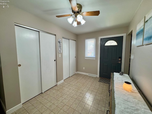 entryway featuring light tile patterned floors, ceiling fan, and baseboards