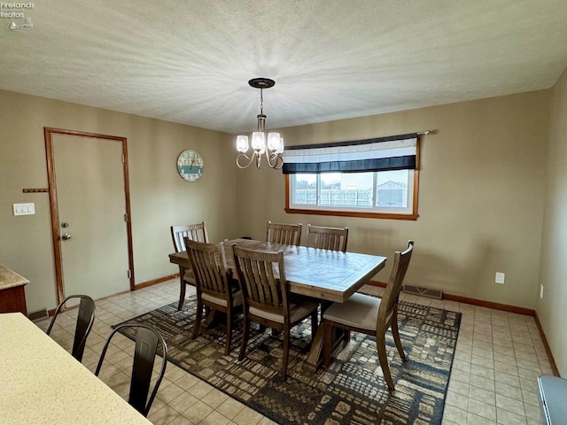 dining space with a textured ceiling, light tile patterned floors, baseboards, and a notable chandelier