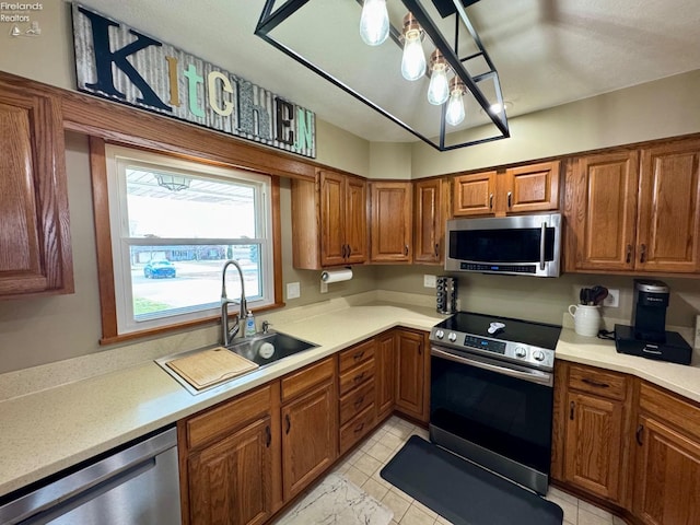 kitchen with brown cabinetry, stainless steel appliances, and a sink