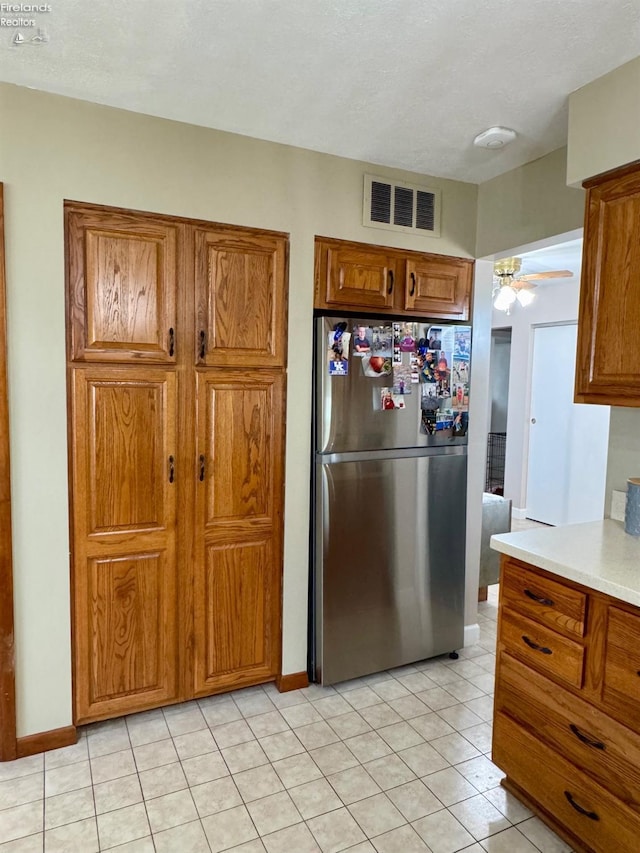 kitchen featuring brown cabinets, light countertops, visible vents, a ceiling fan, and freestanding refrigerator