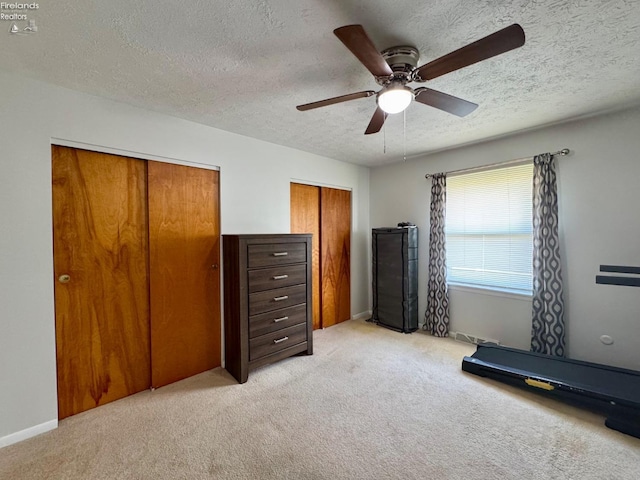 workout room featuring a ceiling fan, a textured ceiling, and light colored carpet