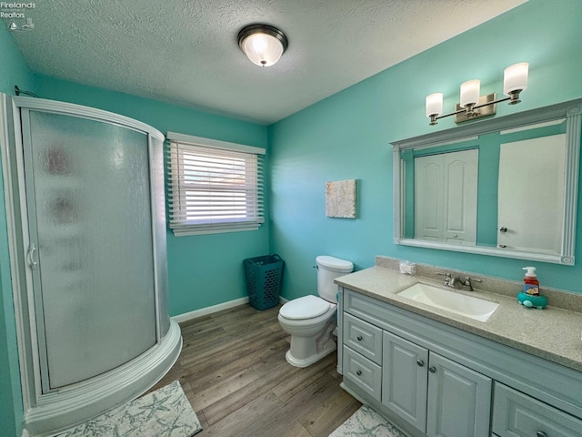 full bathroom with a stall shower, vanity, a textured ceiling, and wood finished floors