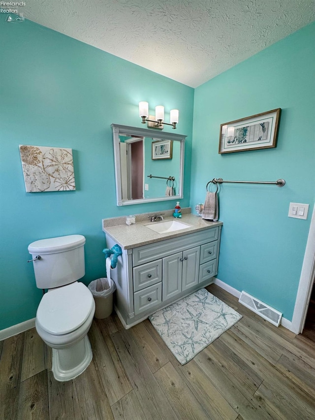 bathroom with a textured ceiling, visible vents, wood finished floors, and vanity