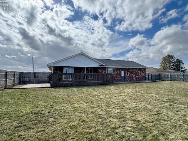 back of house featuring a fenced backyard, a lawn, a deck, and brick siding