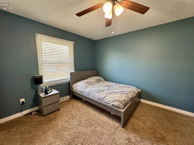 carpeted bedroom with ceiling fan, a textured ceiling, and baseboards