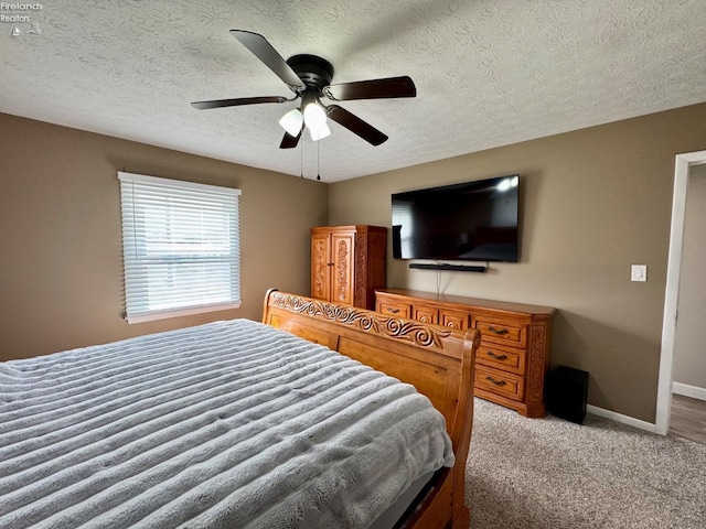 carpeted bedroom with ceiling fan, a textured ceiling, and baseboards