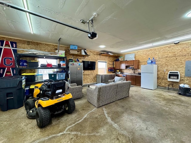 garage with heating unit, electric panel, a garage door opener, and freestanding refrigerator