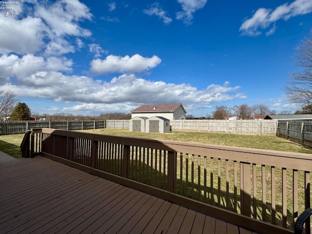 wooden deck featuring an outbuilding, a fenced backyard, a lawn, and a storage shed