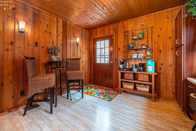 entryway featuring light wood-type flooring, wooden ceiling, and wood walls