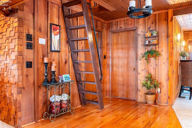 hall featuring wooden ceiling, wooden walls, stairway, and wood finished floors