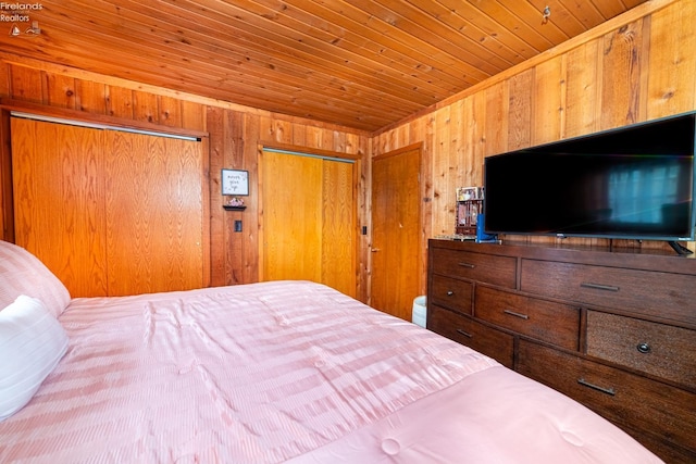 bedroom with wood ceiling, wood walls, and two closets