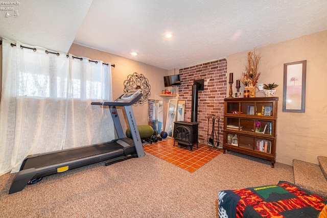 exercise area with carpet, a wood stove, a textured ceiling, and recessed lighting