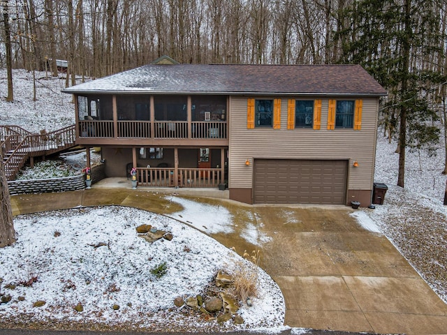 view of front of home with a garage, concrete driveway, and a sunroom