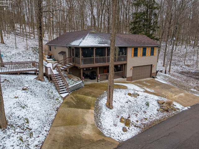 rustic home featuring driveway, a garage, a sunroom, stairway, and a deck