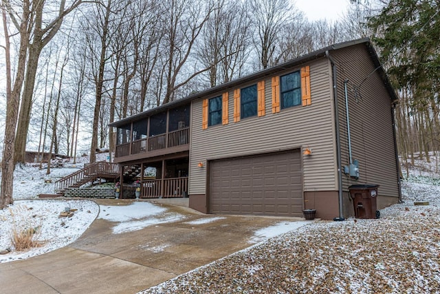 view of front of home featuring a sunroom, stairway, an attached garage, and concrete driveway