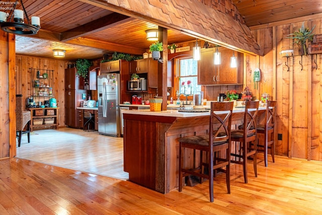 kitchen with light countertops, appliances with stainless steel finishes, wood ceiling, wood walls, and a peninsula