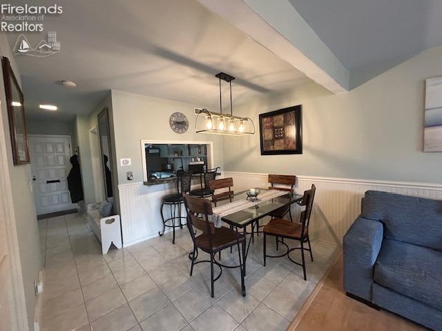 dining room with a wainscoted wall and tile patterned floors