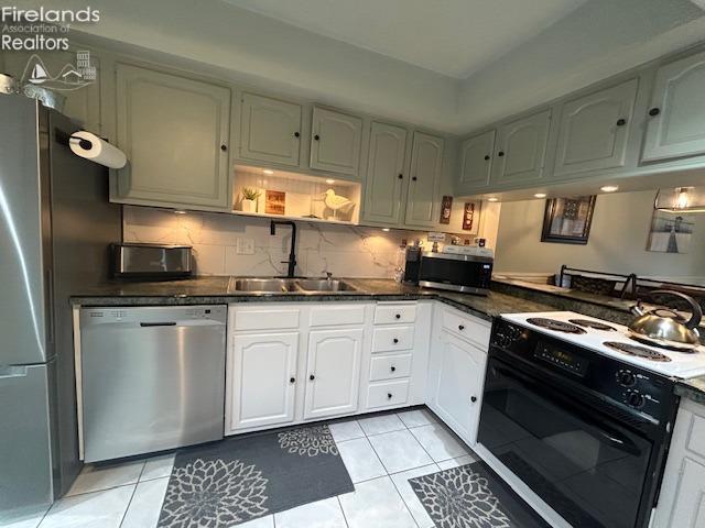 kitchen featuring light tile patterned floors, tasteful backsplash, appliances with stainless steel finishes, white cabinetry, and a sink