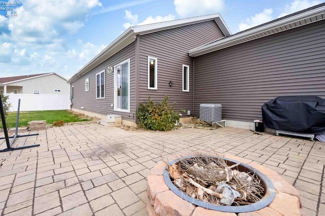 back of property with entry steps, a patio, a fire pit, central AC, and fence